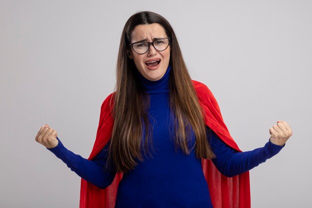 Blij jong superheromeisje die glazen dragen die ja gebaar tonen dat op witte achtergrond wordt geïsoleerd