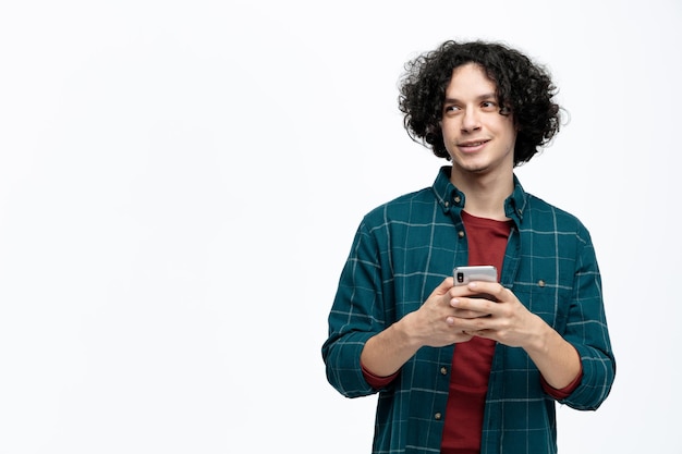 Blij jonge knappe man met mobiele telefoon kijken naar kant geïsoleerd op een witte achtergrond met kopie ruimte Gratis Foto