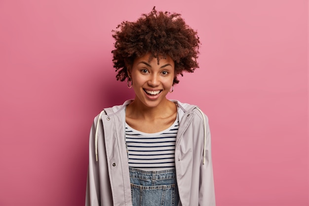 Gratis foto blij lachende vrouw met afro-kapsel, aantrekkelijke look, ontdekt positief nieuws