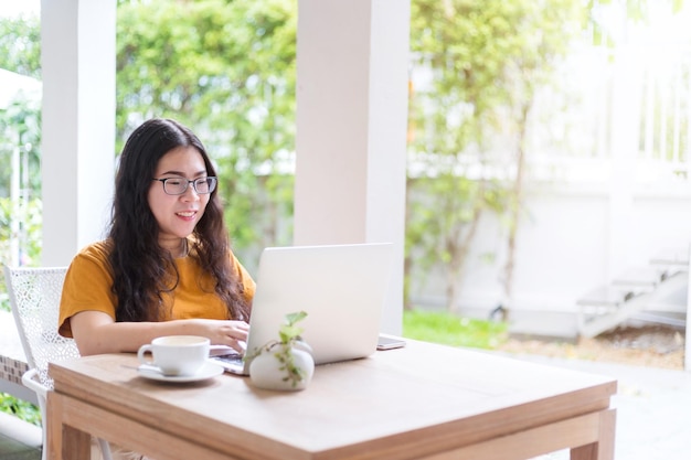 Blij van aziatische freelance mensen zakelijke vrouwelijke casual werken met laptopcomputer met koffiekopje en smartphone in coffeeshop zoals de achtergrond, communicatieconcept