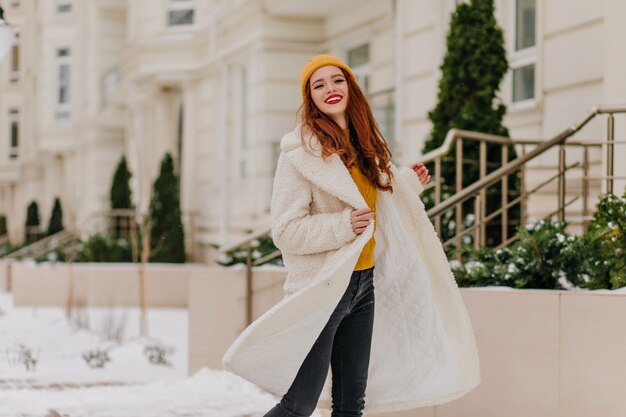 Blije blanke vrouw die in koude ochtend danst. Buitenfoto van onbezorgd gembermeisje dat van de winterdagen geniet.