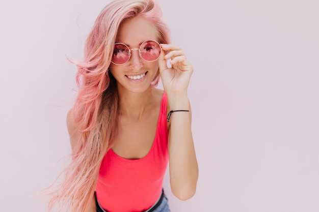 Blije blanke vrouw met roze haar poseren met schattige glimlach.