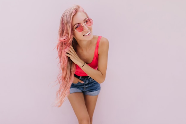 Blije blanke vrouw met roze haar poseren met schattige glimlach.