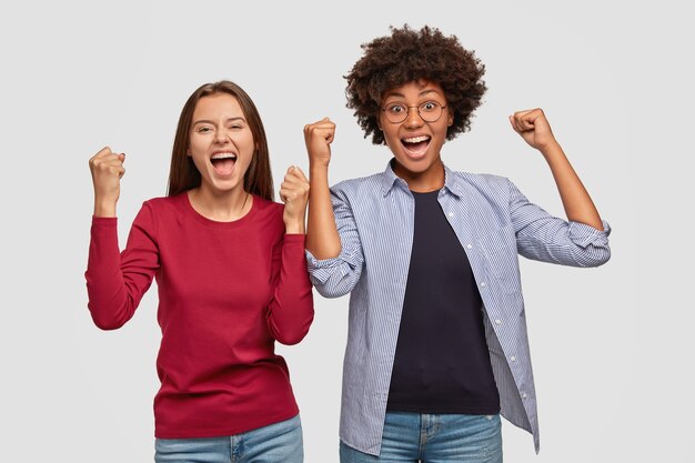 Blije dolgelukkige vrouwen heffen gebalde vuisten op