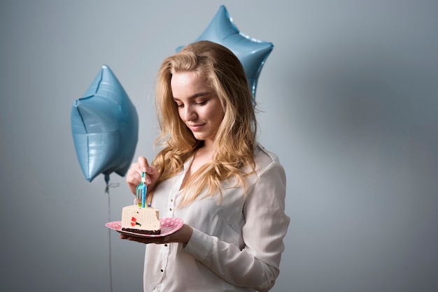 Blije jonge vrouw die verjaardagscake eet