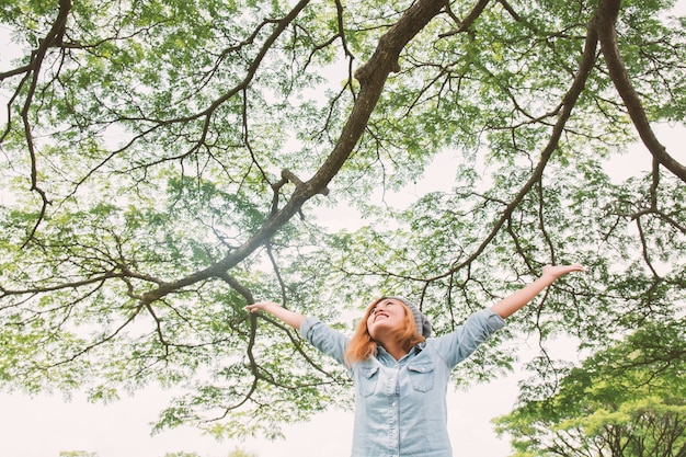 Gratis foto blije jonge vrouw met takken boom achtergrond