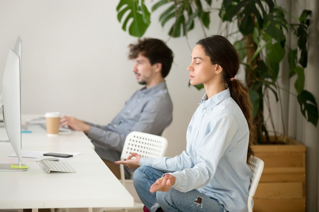 Blije kalme jonge vrouw die onderbreking in bureau voor meditatie neemt