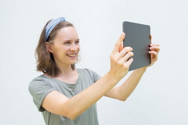 Blije mooie vrouw die tablet voor het nemen van foto's gebruiken