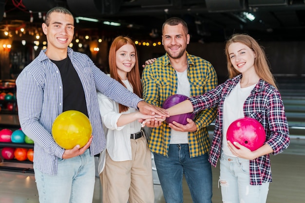 Blije vrienden met bowlingballen in een bowlingclub