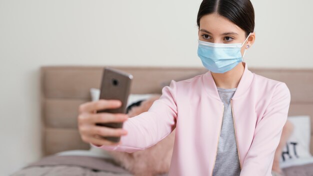 Blijf binnenshuis vrouw met medisch masker selfies nemen