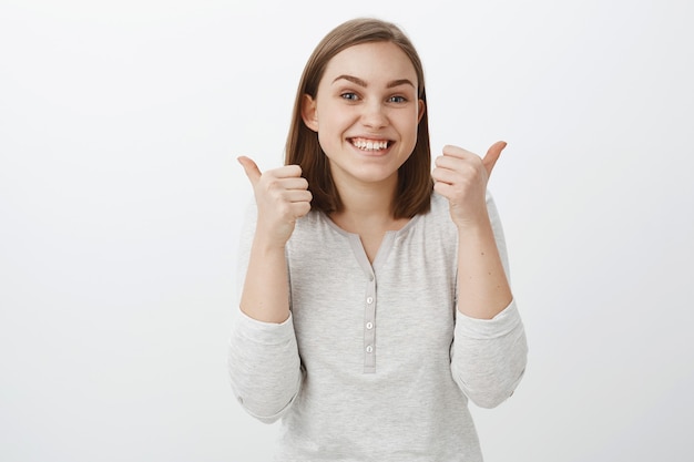 Blijf het goed doen. Portret van charmante vriendelijk ogende vrouw juichen van vriend die hem steunt op competitie, duimen opheffen van gejuich en graag blij staan, cool idee goedkeuren