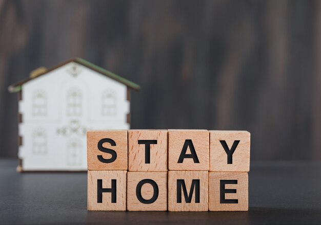 Blijf thuis concept met houten kubussen, huismodel grijs.