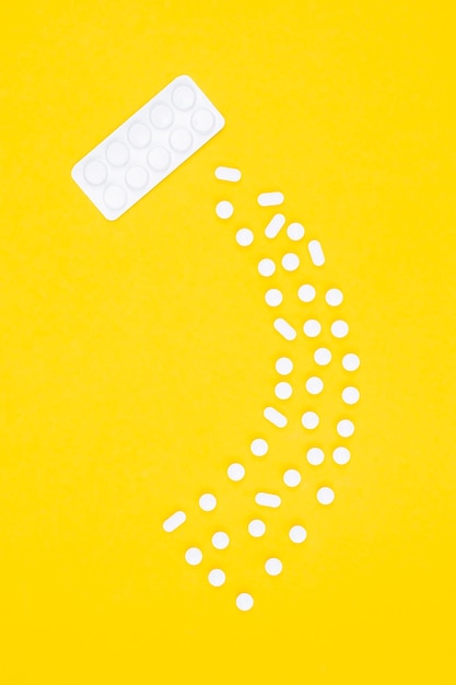 Gratis foto blister met pillen en tabletten op een gele achtergrond plat gelegd