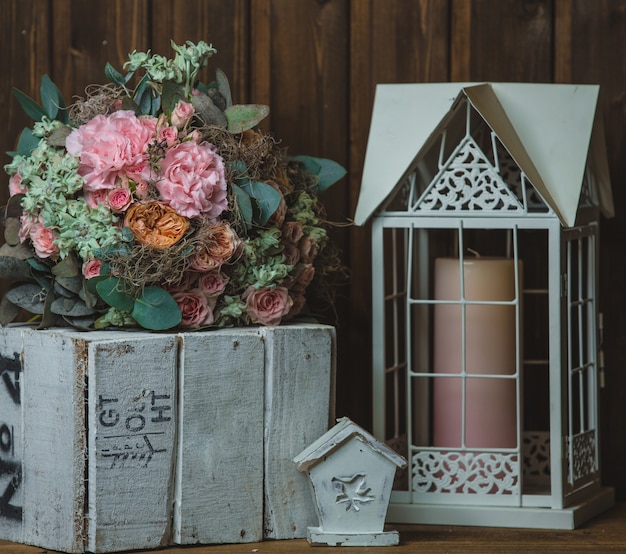 Gratis foto bloemboeket, kaars in de kooi en rustieke houten kist