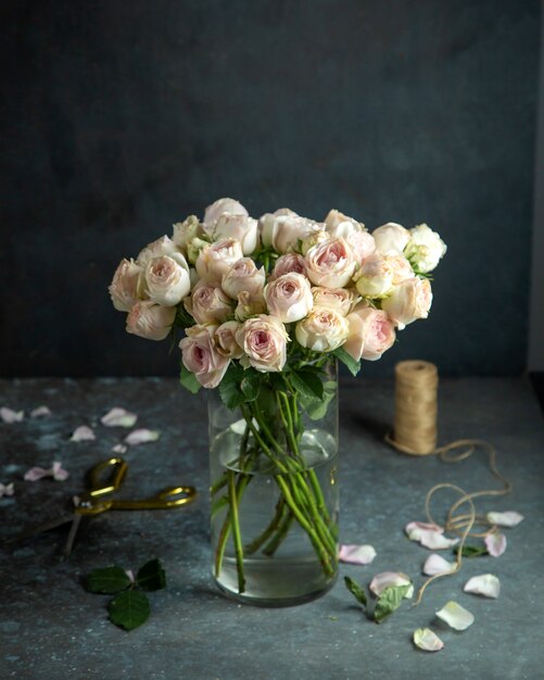 bloemen decor lichtroze rozen in vaas schaar touw en rozenblaadjes op zwart