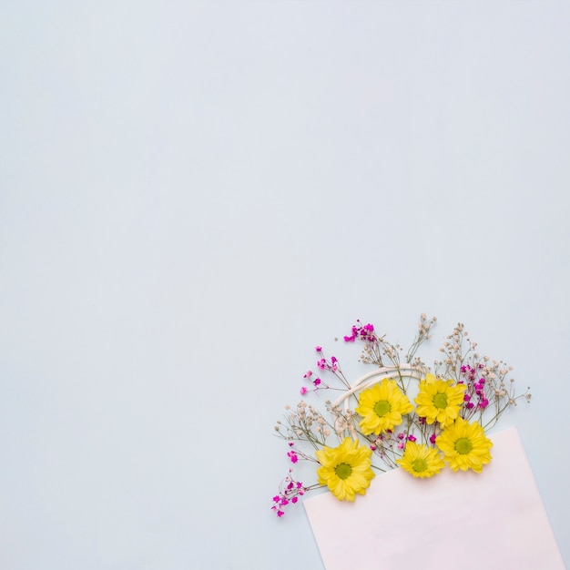 Bloemen die uit de roze document zak komen tegen witte achtergrond