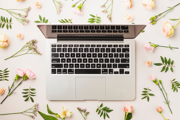 Gratis foto bloemen en bladeren rond laptop