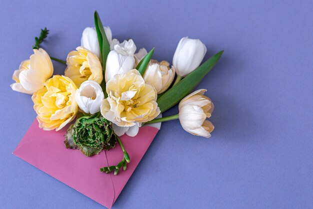 Bloemen in een envelop op een gekleurde achtergrond plat gelegd