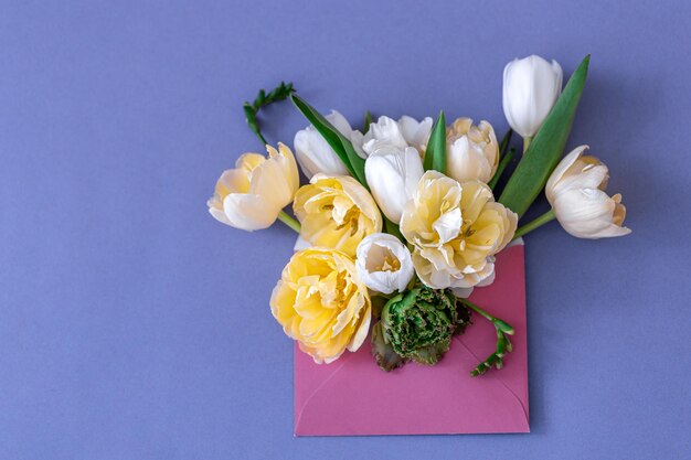 Bloemen in een envelop op een gekleurde achtergrond plat gelegd