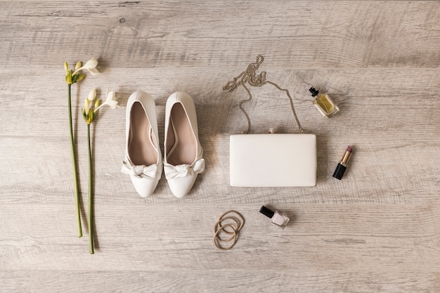 bloemen; kleding schoenen; koppeling; parfum; lippenstift; nagellak en haarbanden op houten achtergrond