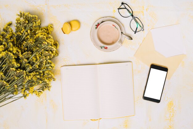 Bloemenboeket met smartphone, koffie en notitieboekje op lijst