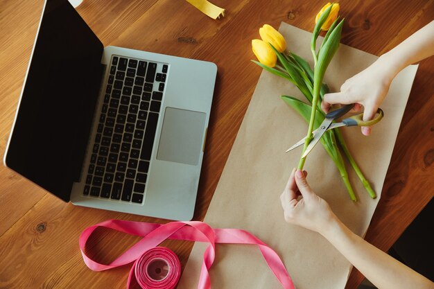 Bloemist aan het werk: vrouw laat zien hoe je een boeket met tulpen maakt.