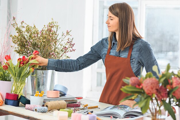 Bloemist op het werk: het jonge meisje dat mode modern boeket van verschillende bloemen maakt