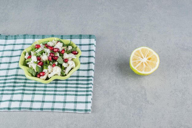 Bloemkoolsalade met rode granaatappelpitjes in een plaat.