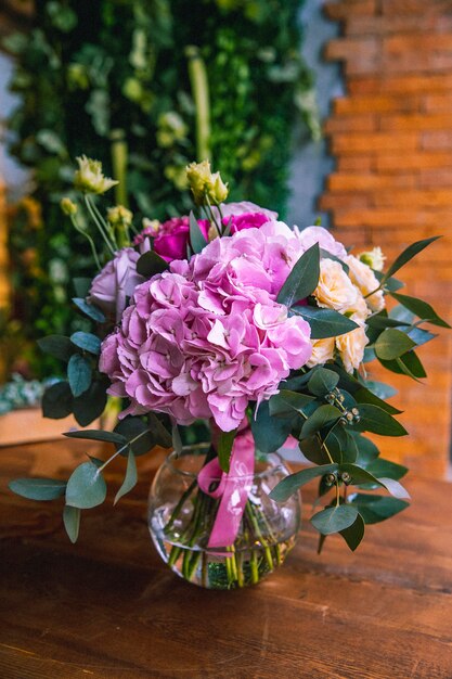 Bloemsamenstelling in zijaanzicht van de hortensia's het heldere oranje rozen van de glasvaas