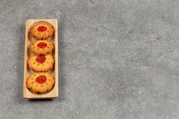 Bloemvormige koekjes met gelei op houten bord