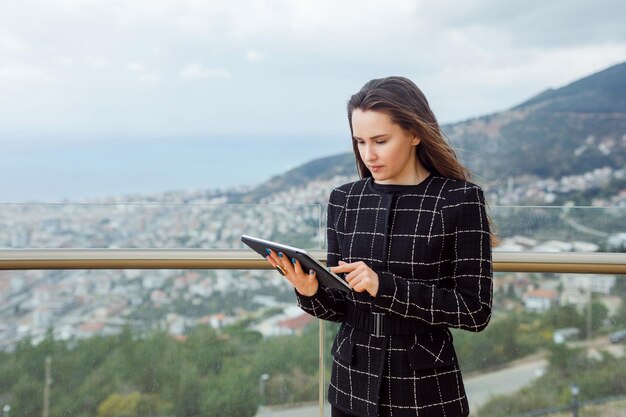 Blogger-meisje gebruikt een planhet-computer tegen de achtergrond van uitzicht op de stad