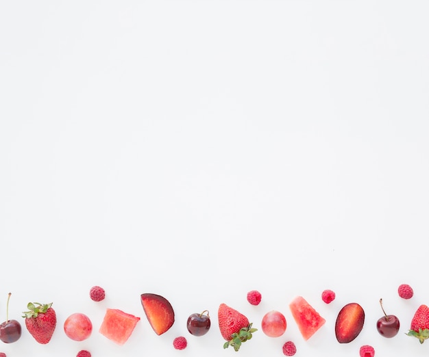 Blokjes watermeloen; frambozen; Pruim; kersen en aardbeien aan de zijkant van witte achtergrond