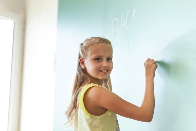 Blond lachend meisje schrijven op schoolbord