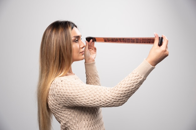 Blond meisje aandachtig controleren van foto's op fotorolletje.