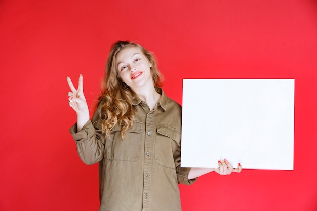 Blond meisje dat naar een canvas kijkt en ervan geniet.