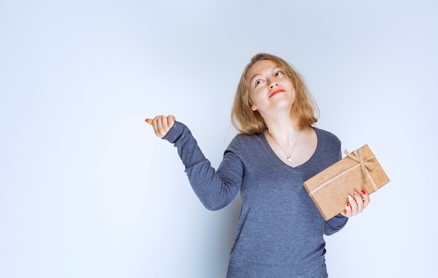 Blond meisje demonstreert haar kartonnen geschenkdoos en voelt zich positief.