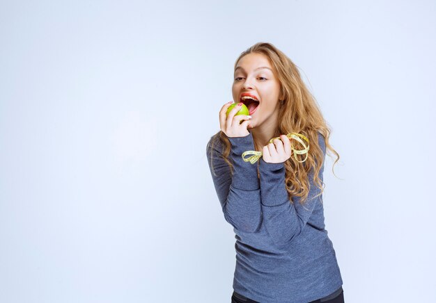 Blond meisje een groene appel bijten.