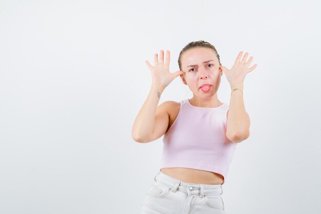 Blond meisje haalt tong uit op witte achtergrond