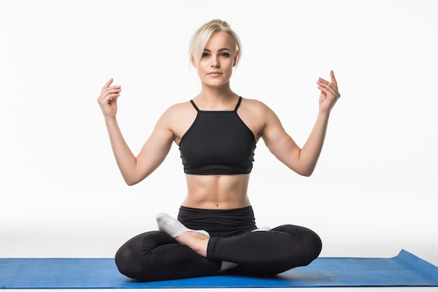 Blond meisje heeft een ontspannen yoga-tijd na sportoefening op de vloer zittend op een sportkaart