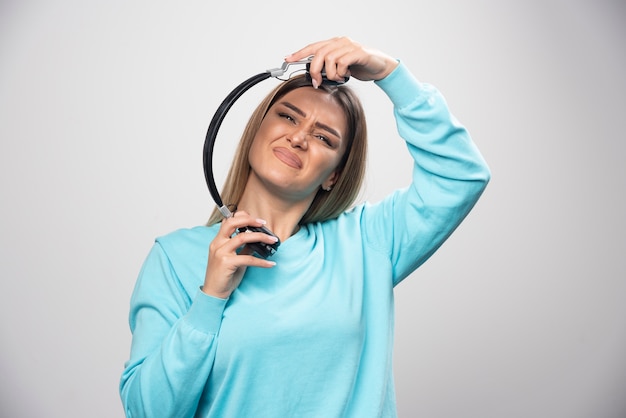 Blond meisje in blauw sweatshirt luistert naar de koptelefoon en geniet niet van de muziek