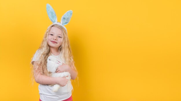 Blond meisje in konijntjesoren met konijn