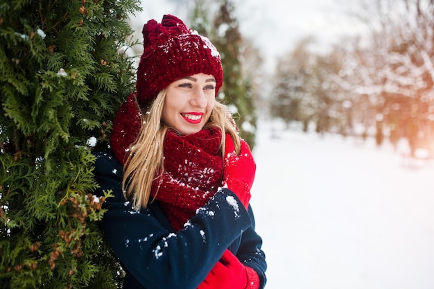 Blond meisje in rode sjaal en jas wandelen in het park op winterdag