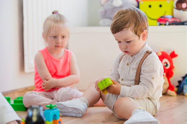 Blond meisje kijken naar het spelen van de jongen