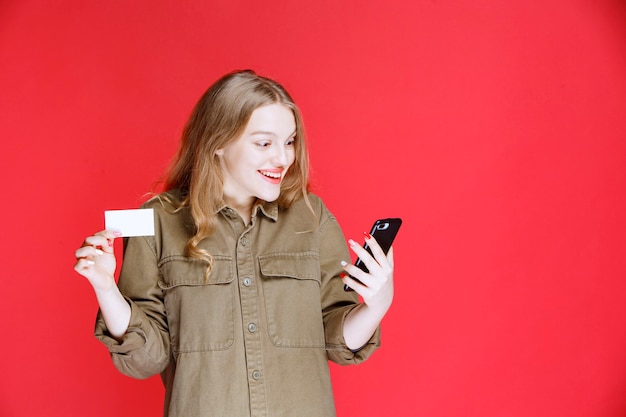 Blond meisje met een visitekaartje en praten met de telefoon.