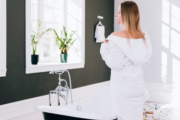 Blond meisje poseren in de badkamer met badjas