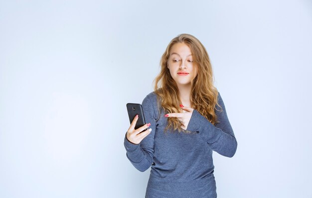 Blond meisje sms't en verzendt berichten met haar smartphone.