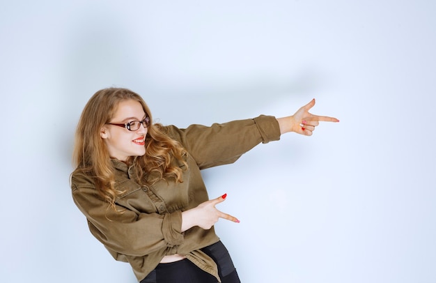 Gratis foto blond meisje wijzend naar iemand aan de rechterkant.