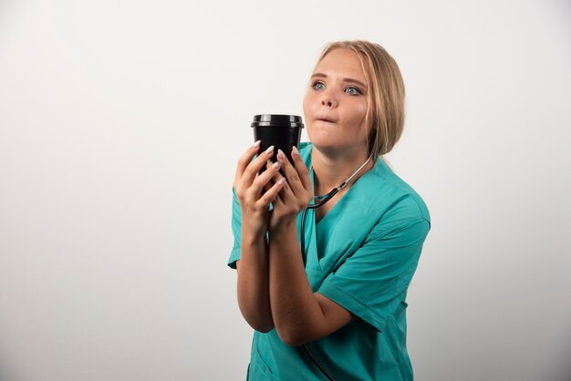 Blonde arts poseren met een kopje koffie.