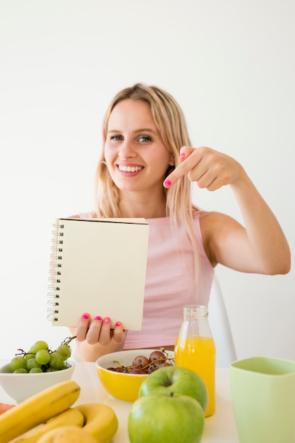 Blonde beïnvloeder die notitieboekje toont