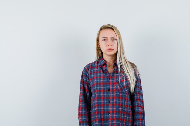 Blonde dame camera in casual shirt kijken en boos, vooraanzicht kijken.